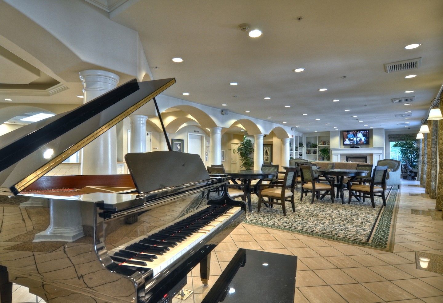 Interior view of Ivy Park at Mission Viejo senior living community featuring a grand piano and modern decor.