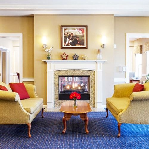 Senior enjoying cozy living room with fireplace and art decor at All American Assisted Living, Washington Township.