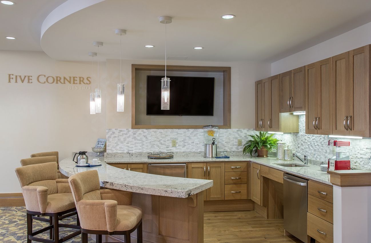 Interior view of The Residence At Five Corners senior living community featuring a well-designed kitchen, modern furniture, and electronics.
