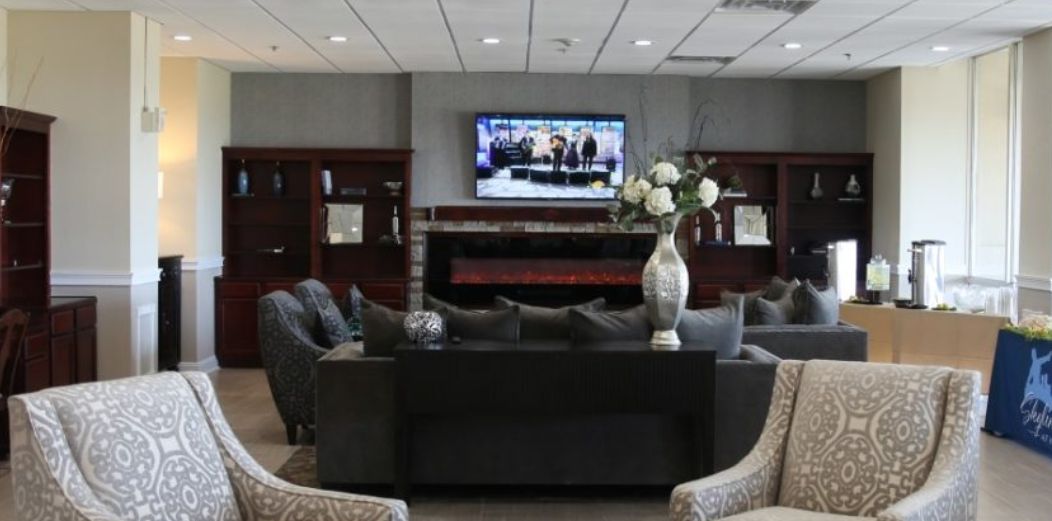 Senior living room interior at Skyline Village, featuring modern decor, electronics, and residents.
