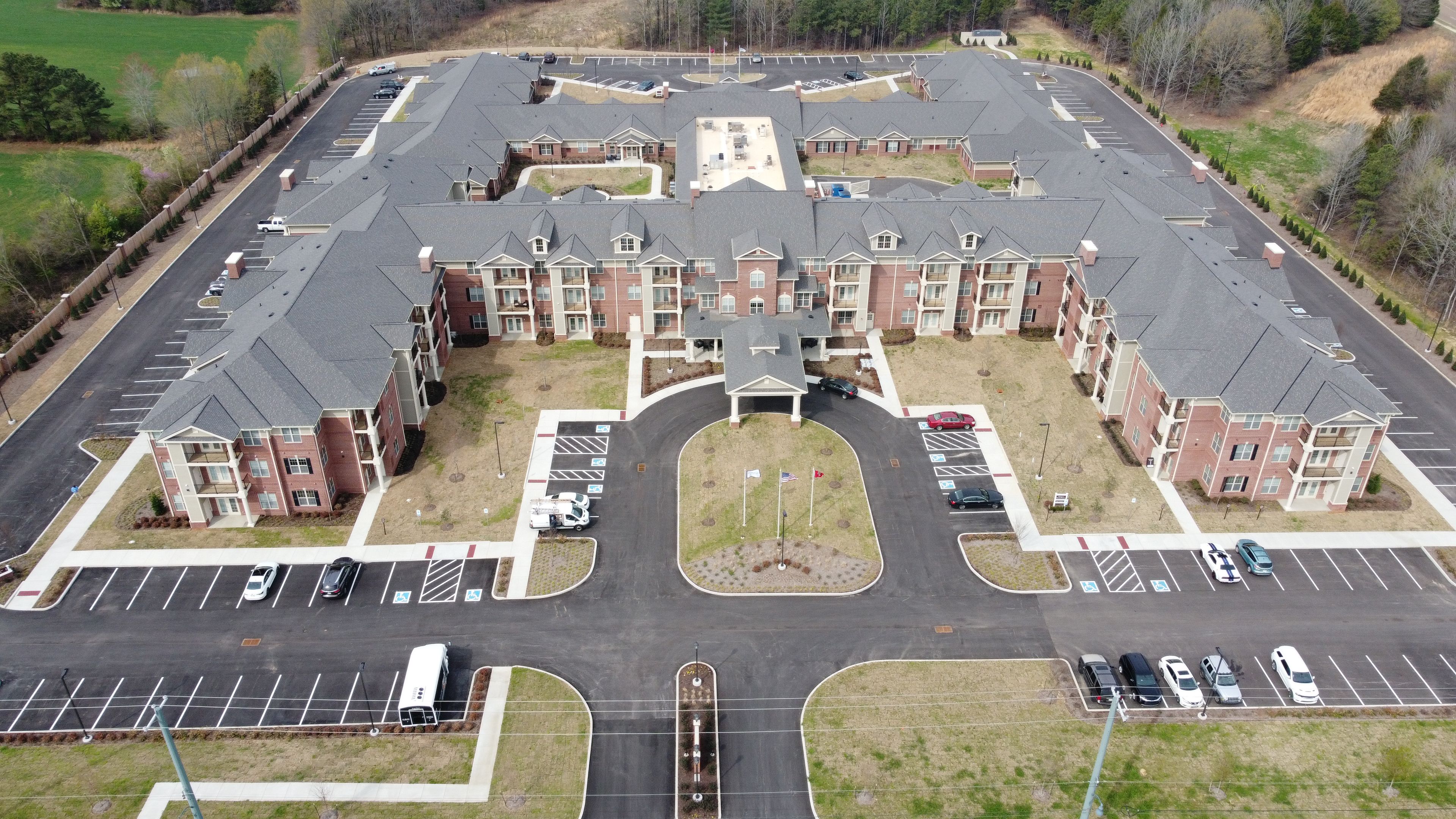 Aerial view of Storypoint Collierville senior living community with buildings, houses, and vehicles.