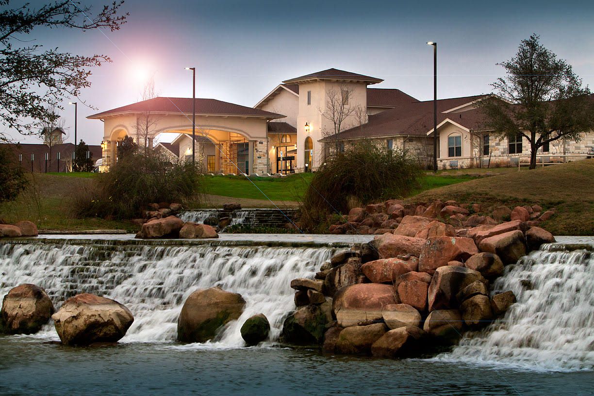 Senior living community at Franklin Park Round Rock with lush landscape, pond, and waterfall.