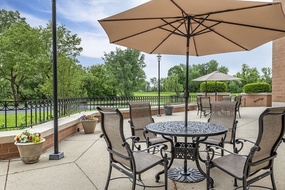 Senior enjoying scenic outdoors at Brookdale Hoffman Estates with patio furniture and housing.