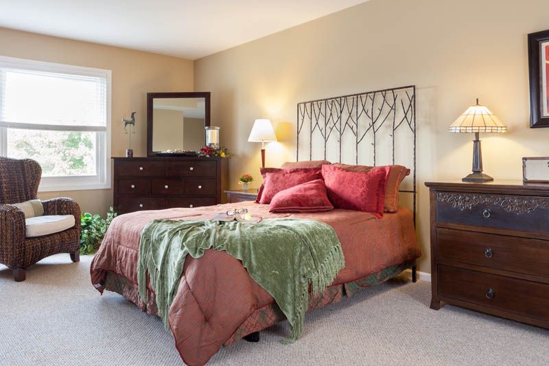 Senior living room interior at The Fountains At Crystal Lake with bed, lamp and home decor.