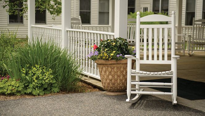 Kimball Farms Nursing Care Center featuring a porch with rocking chairs, potted plants, and outdoor furniture.