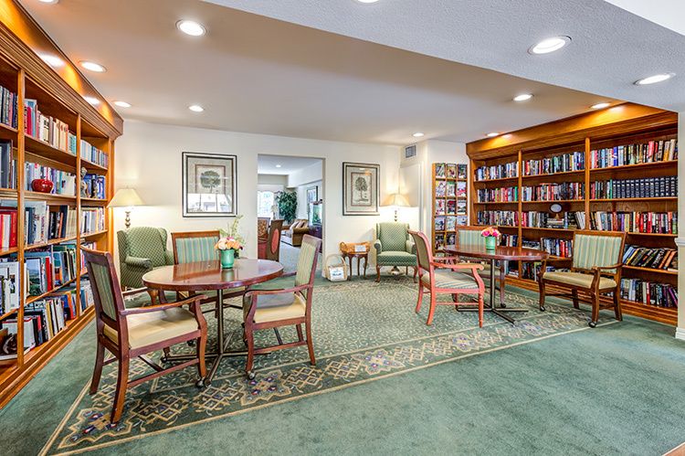 Senior living community library at Park Plaza with bookcases, dining tables, and home decor.