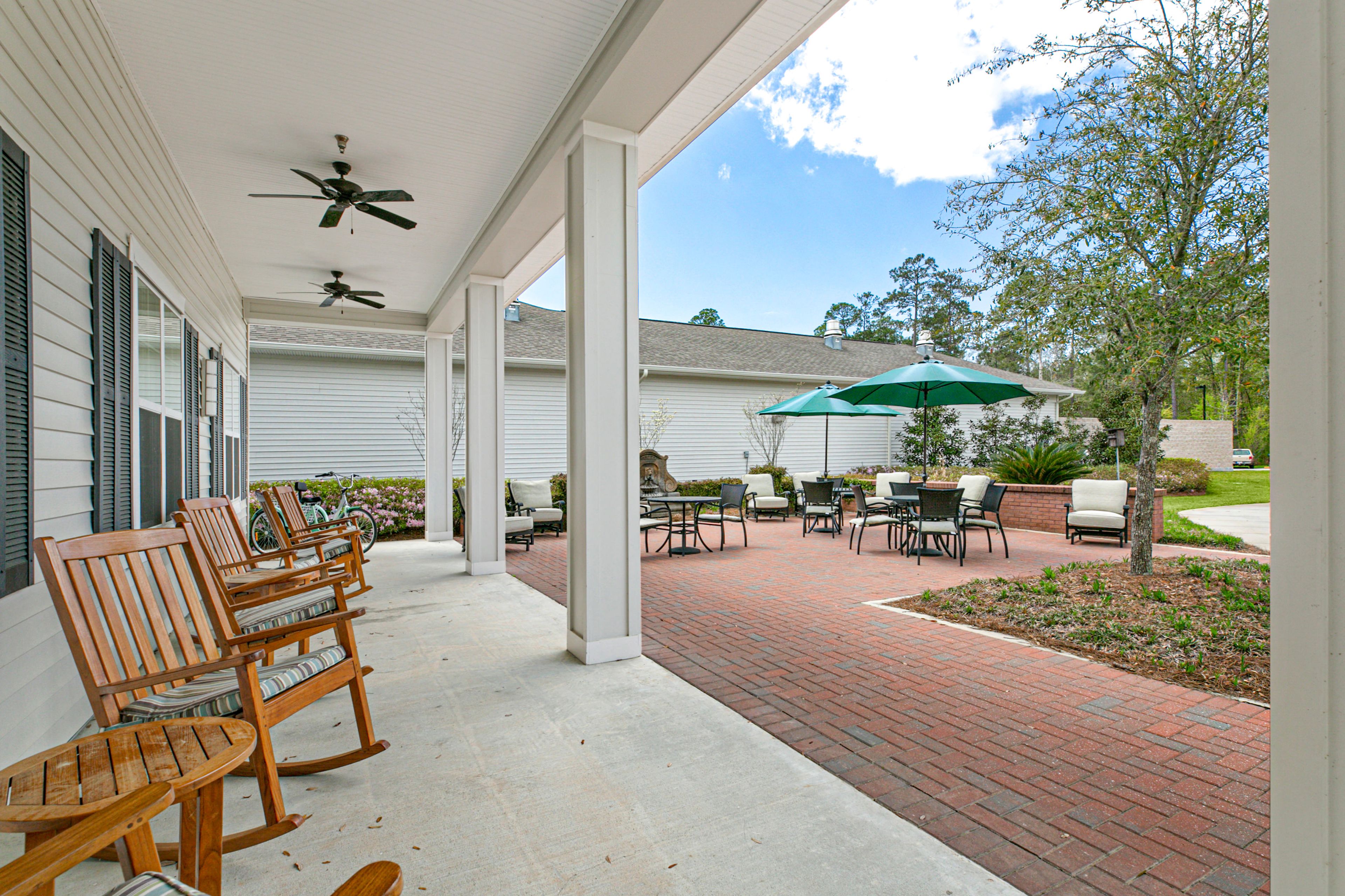 Senior living community, St. Anthony's Gardens, featuring a path, patio with furniture, and indoor amenities.
