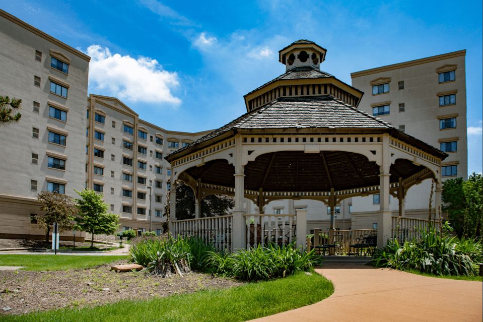 Outdoor view of Lexington Square Lombard senior living community with gazebo and fir trees.