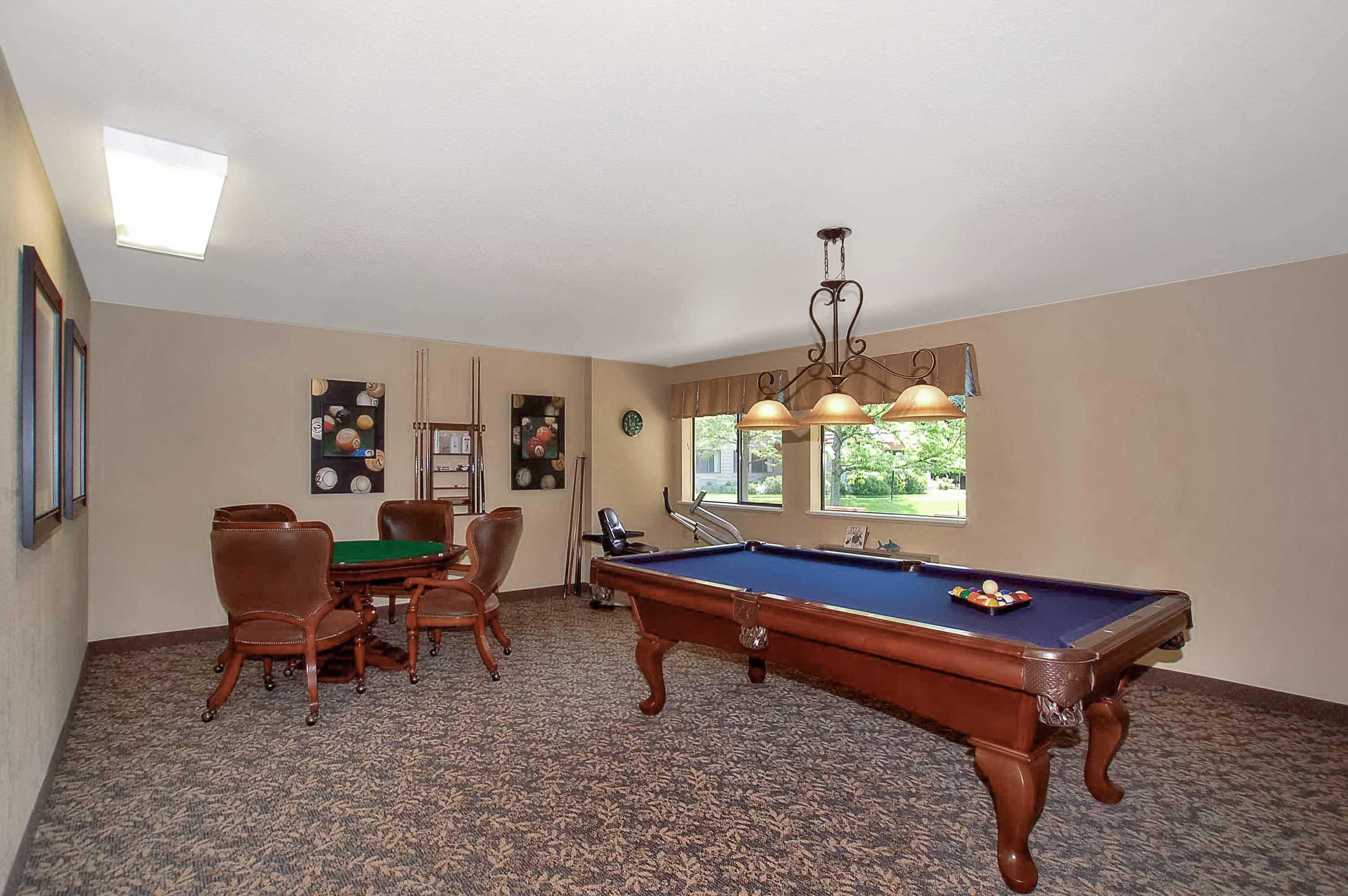 Senior living community billiard room at Parkwood Estates with furniture, pool table, and cricket sport gear.