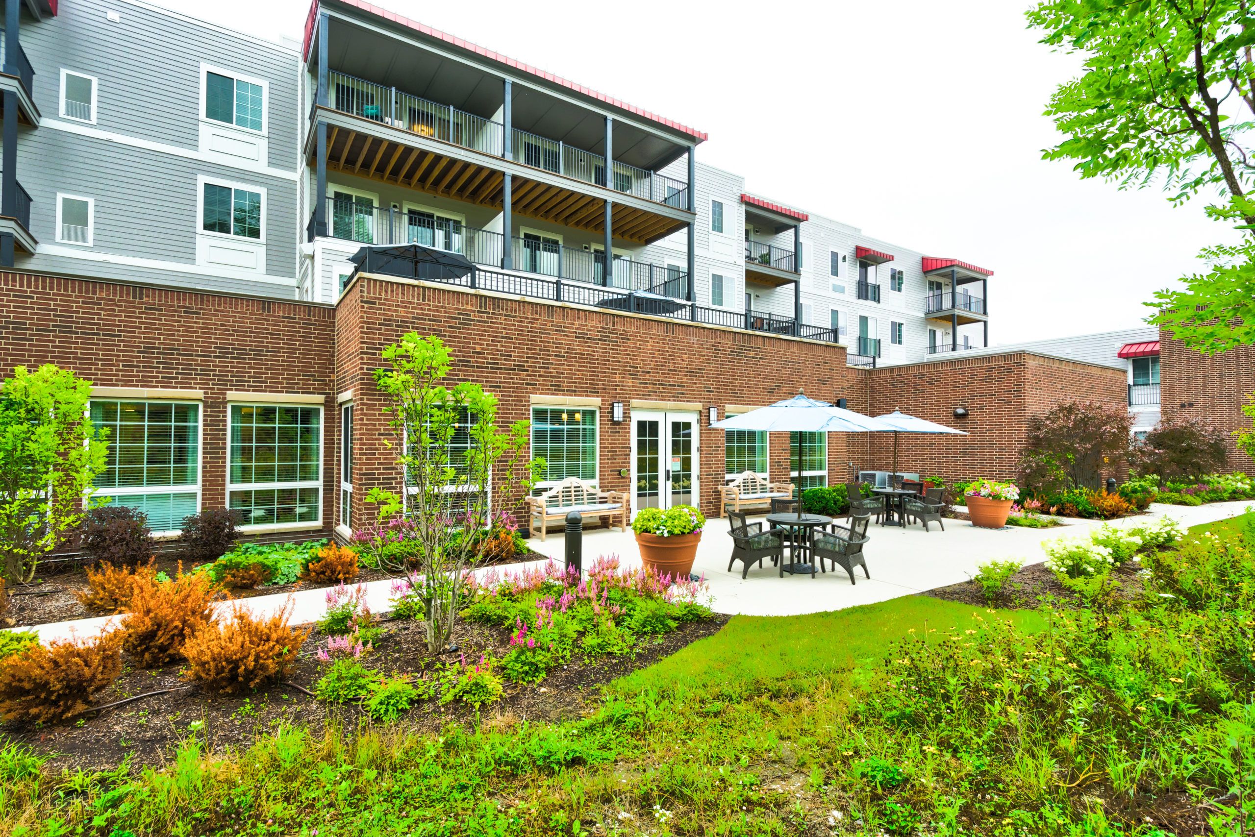 Senior living community in Palos Heights with high-rise apartments, outdoor benches, and lush greenery.