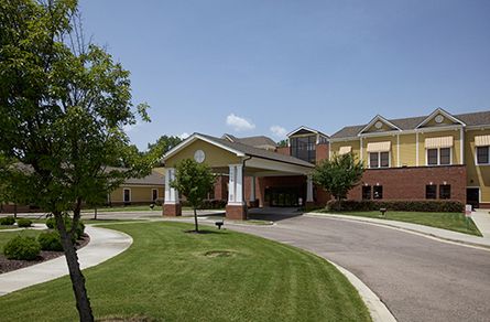 Senior living community, AHC Savannah, featuring lush lawns and plants in a suburban city setting.