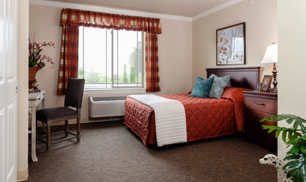 Senior living community bedroom at Robinwood Landing with cozy furniture, art, and pet dog.