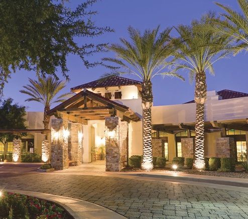 Exterior view of The Village at Ocotillo senior living community with lush greenery.