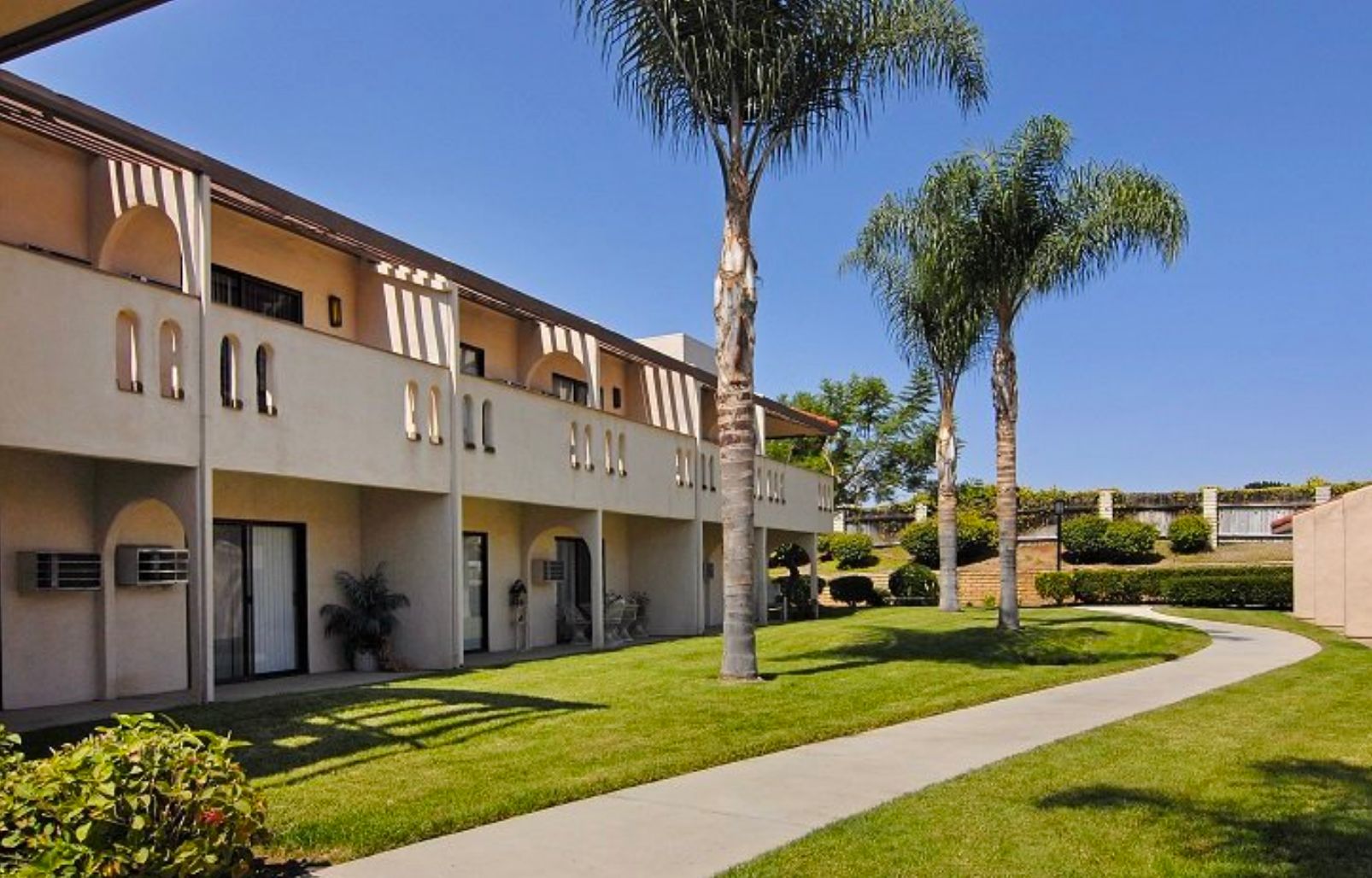 Architectural view of Pacifica Senior Living Vista, a suburban villa with lush lawns and urban trees.
