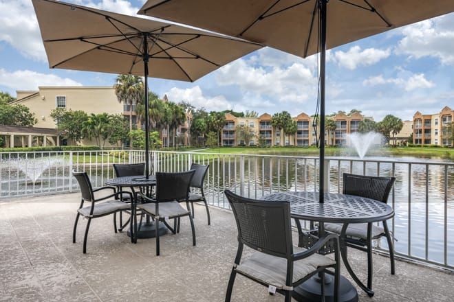 Scenic view of Brookdale West Palm Beach senior living community with lakefront housing and outdoor furniture.
