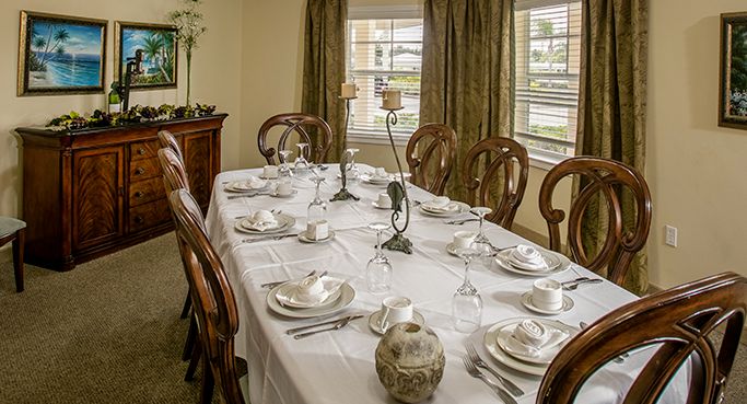 Senior living community dining room at Water's Edge of Lake Wales with wooden furniture and floral decor.