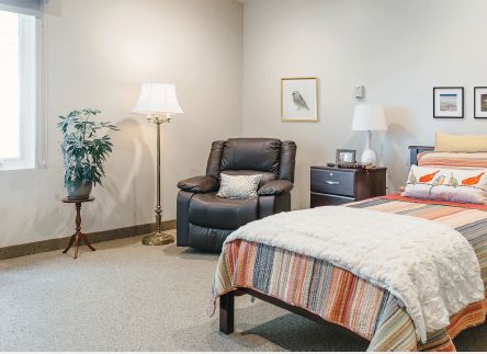 Senior living room at Holland Home's Raybrook Manor with cozy bed, chair, and home decor.