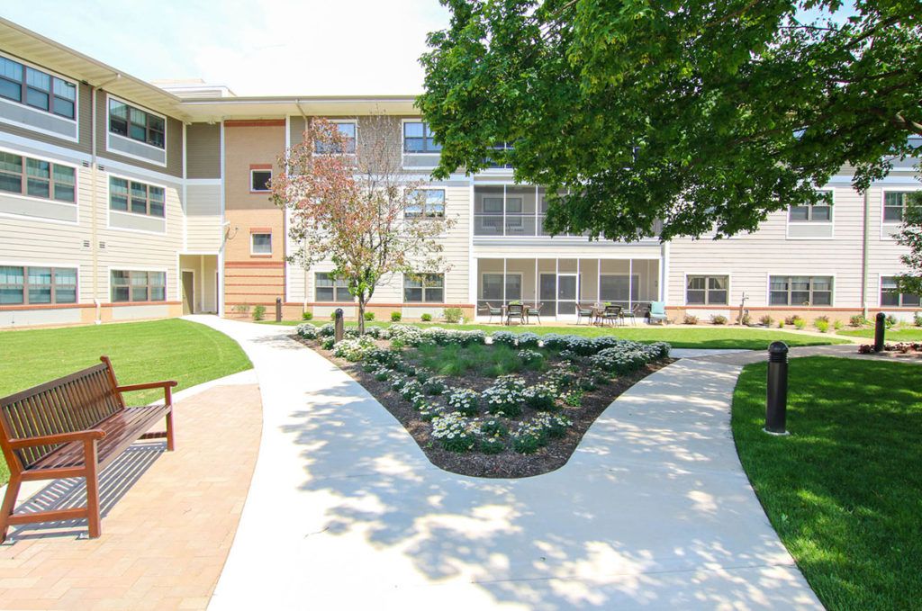 Senior living community, Lutheran Hillside Village, with lush lawns, park benches, and urban condos.