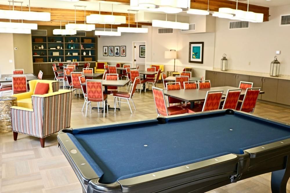 Seniors enjoying billiards in the indoor game room at Sunnycrest Senior Living community.