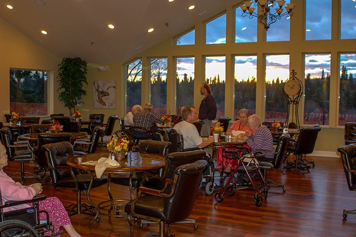 Seniors enjoying mealtime in the spacious dining area of Riverside Assisted Living, Soldotna.