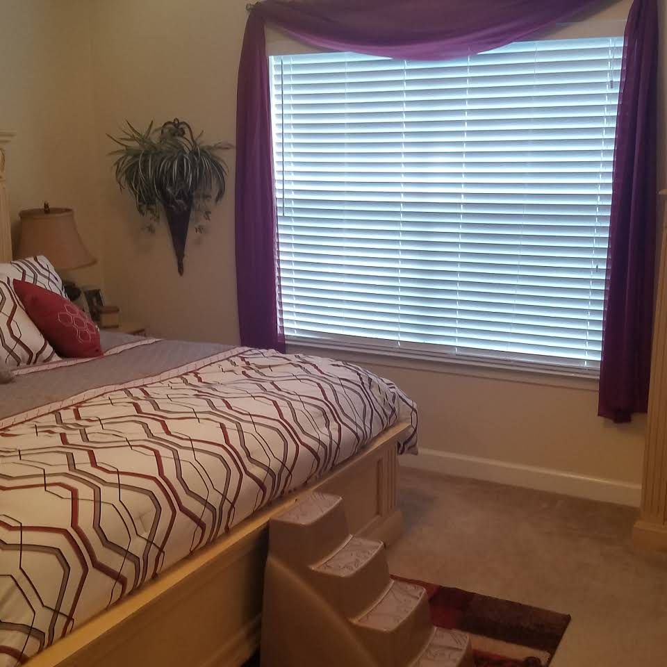 Interior view of a well-decorated bedroom with bay window at Gordon Oaks Senior Living Community.