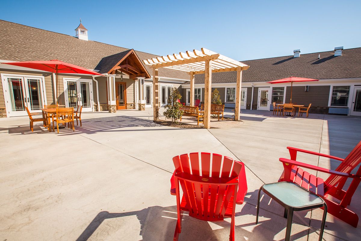Senior living community architecture featuring indoor and outdoor spaces with patio furniture.