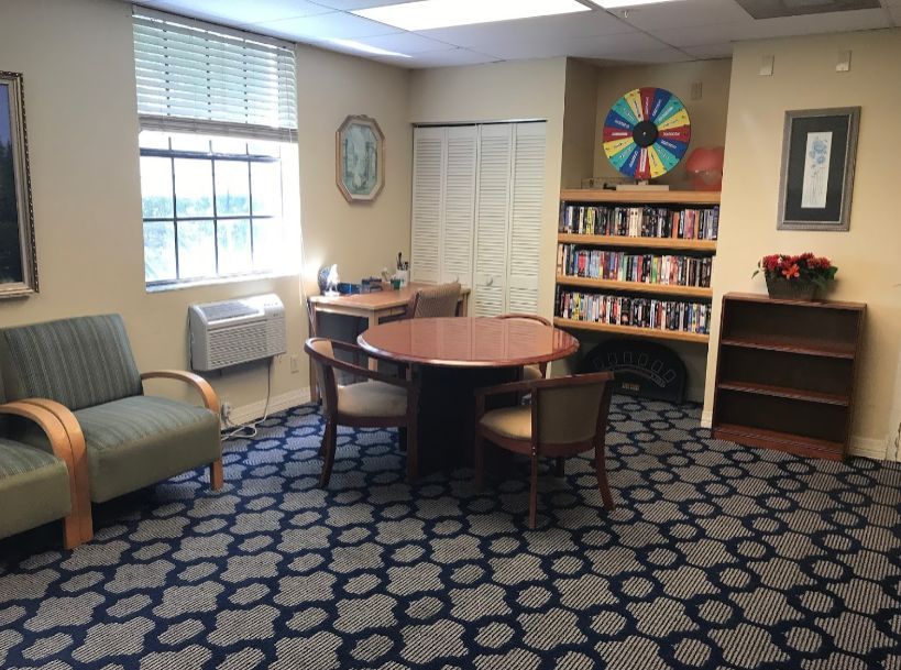 Interior view of Atlantis Assisted Living featuring cozy furniture and library in the lounge area.