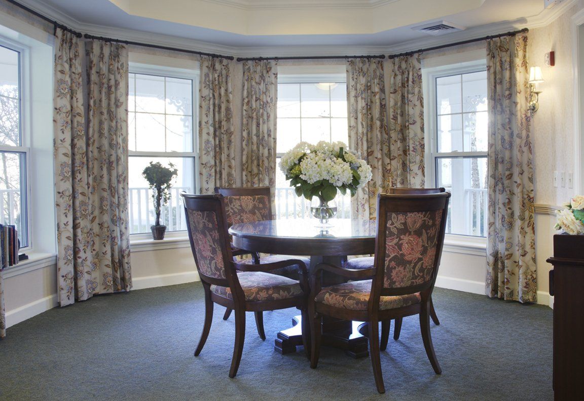 Senior living community dining room at Sunrise of Schaumburg with bay window, table and flower decor.