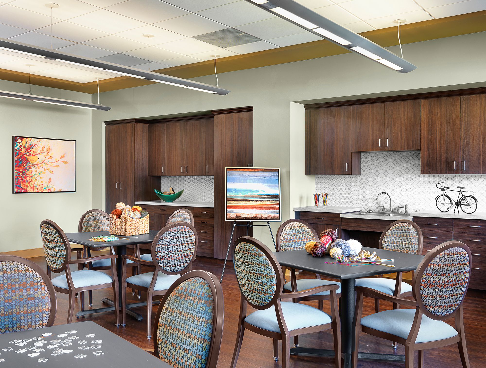 Interior view of Kingswood senior living community featuring dining area, kitchen, and art decor.