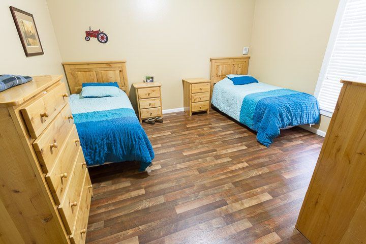 Interior view of a bedroom in Ashley Manor Arlington, featuring hardwood flooring and furniture.