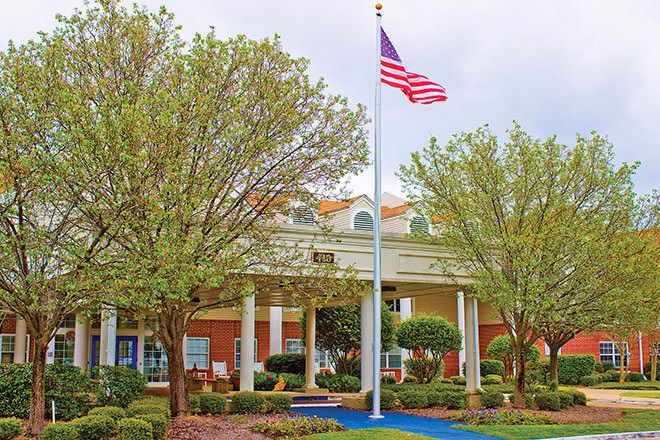 American flag flying at the portico of Ridgeland Place, a senior living community building.