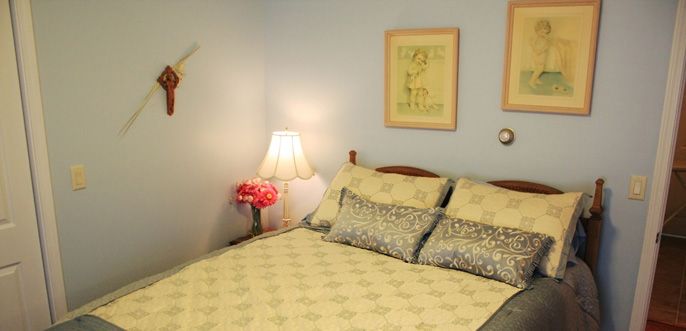 Senior living bedroom at Hopedale Commons with modern decor, furniture, and a ceiling fan.