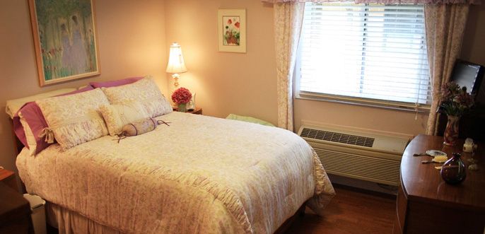 Interior view of a furnished bedroom in Hopedale Commons senior living community.