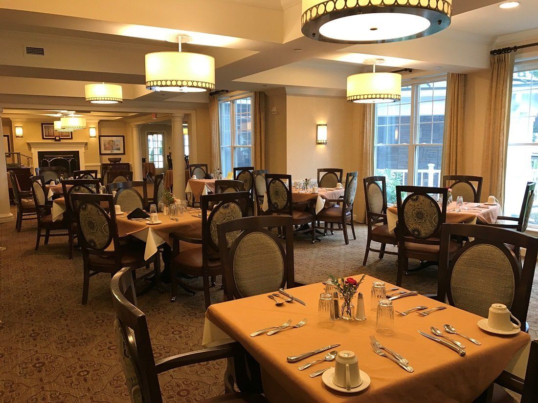 Senior living community dining room at Sunrise of Cresskill with art, furniture, and cutlery.