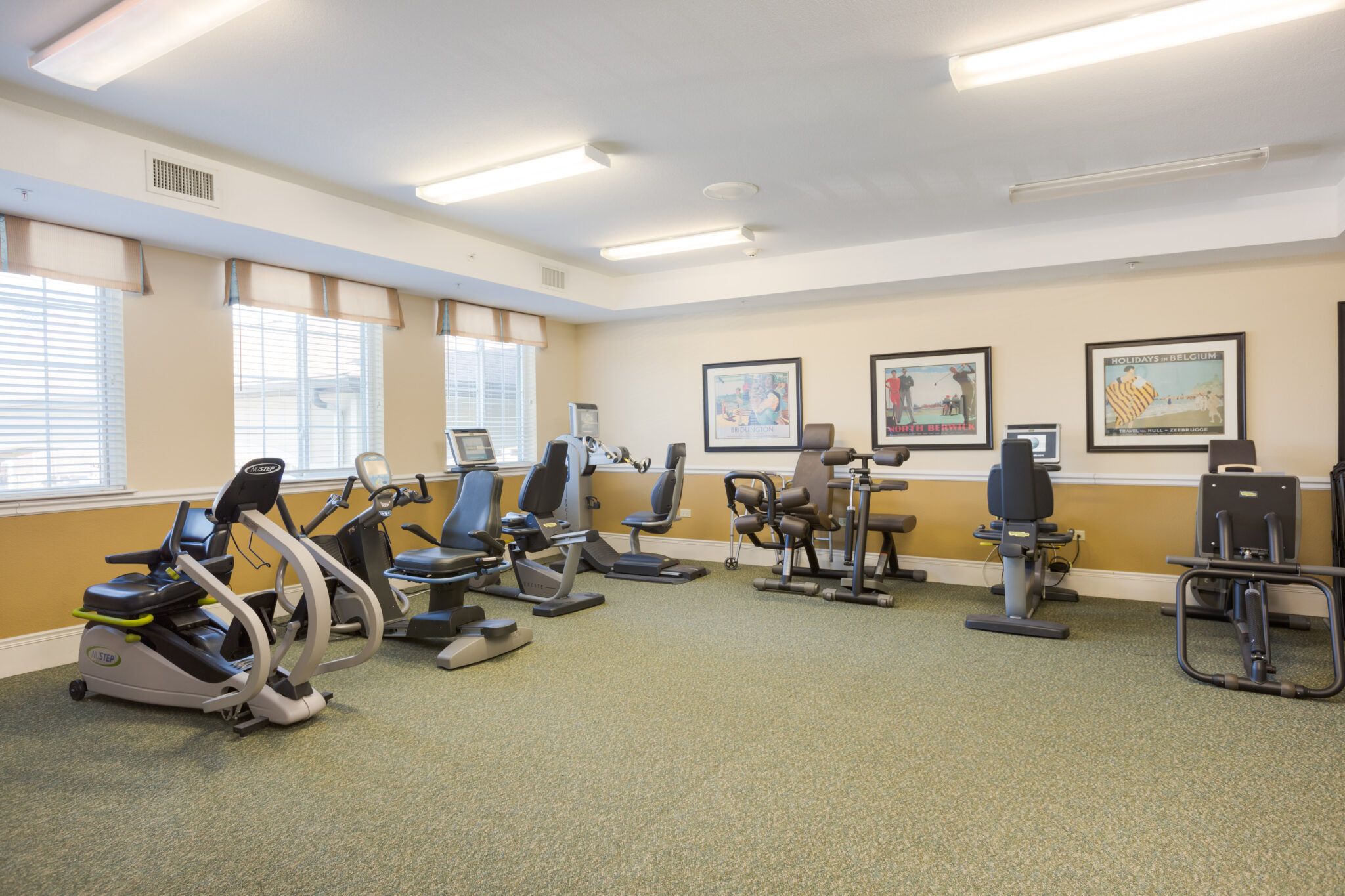 Senior resident at Three Oaks Assisted Living working out in gym with modern equipment, surrounded by art.