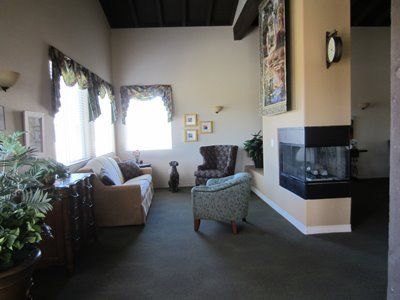 Senior living room interior at Sunny Rose Glen with cozy furniture, plants, and a pet dog.