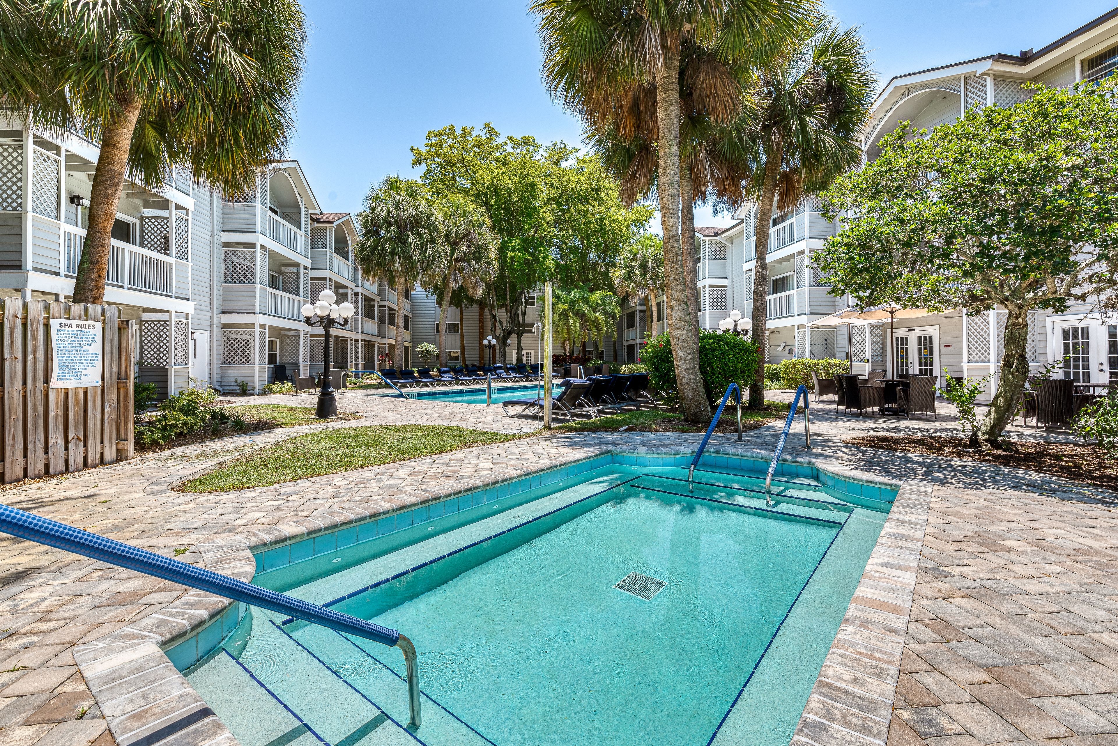 Summer view of The Meridian At Lantana senior living community with pool and lush scenery.