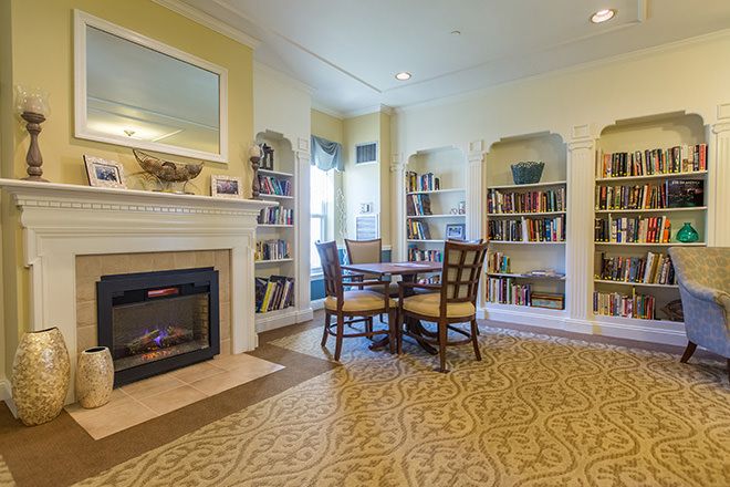 Interior view of Brookdale Cape Cod senior living community featuring a cozy fireplace and library.