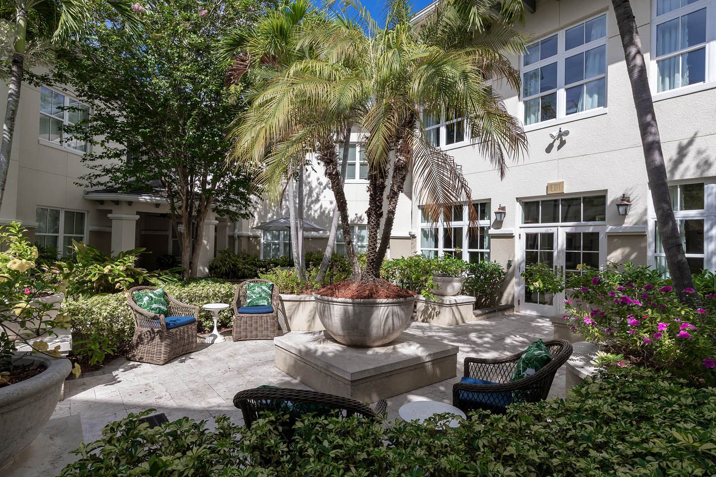 Senior living community, The Estate At Hyde Park, featuring lush gardens, urban architecture, and patio furniture.