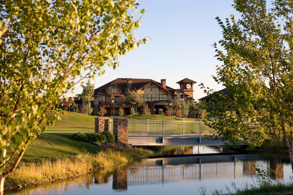 Scenic view of Touchmark At Meadow Lake Village senior living community with lush greenery and lakefront.