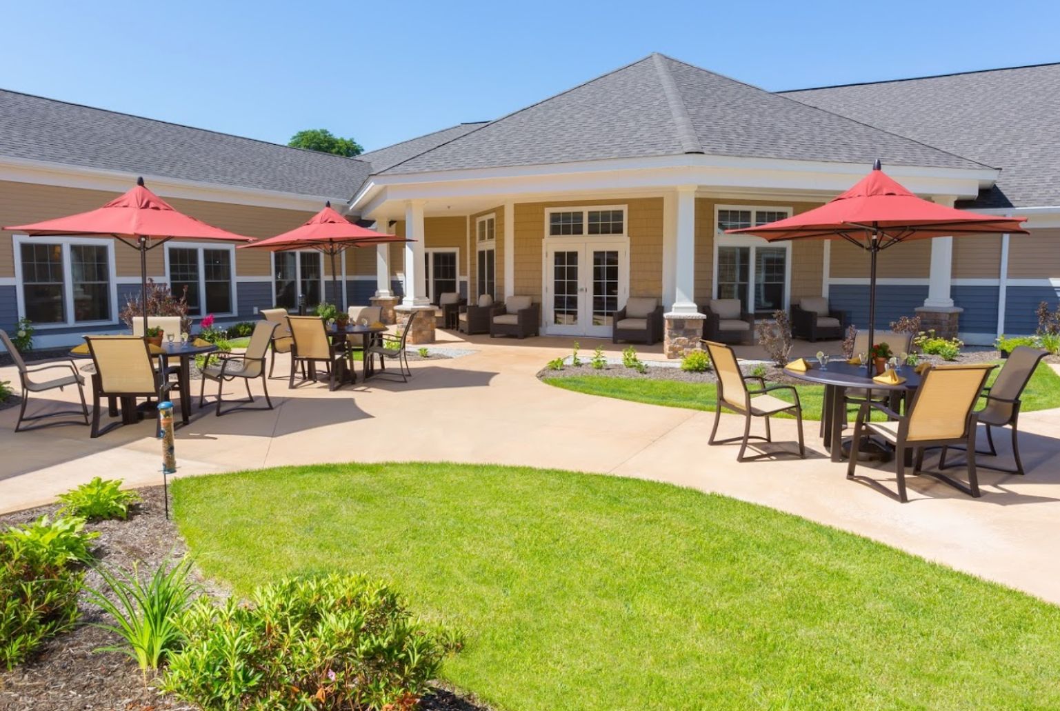 Senior living community, Cornerstone at Milford, featuring lush lawns, patio dining, and modern architecture.