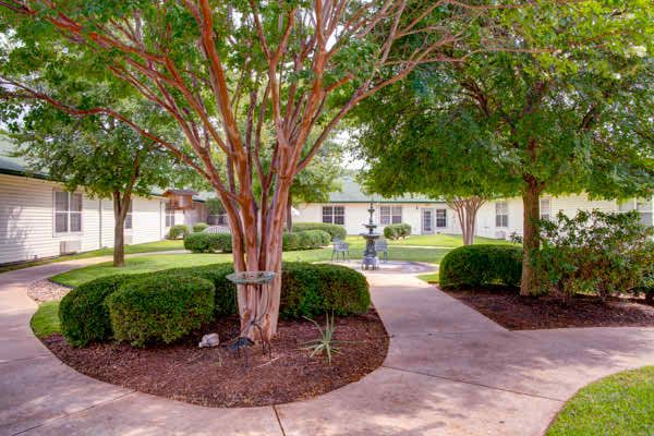 Senior living community, The Pointe At Cedar Park, featuring lush greenery and modern architecture.