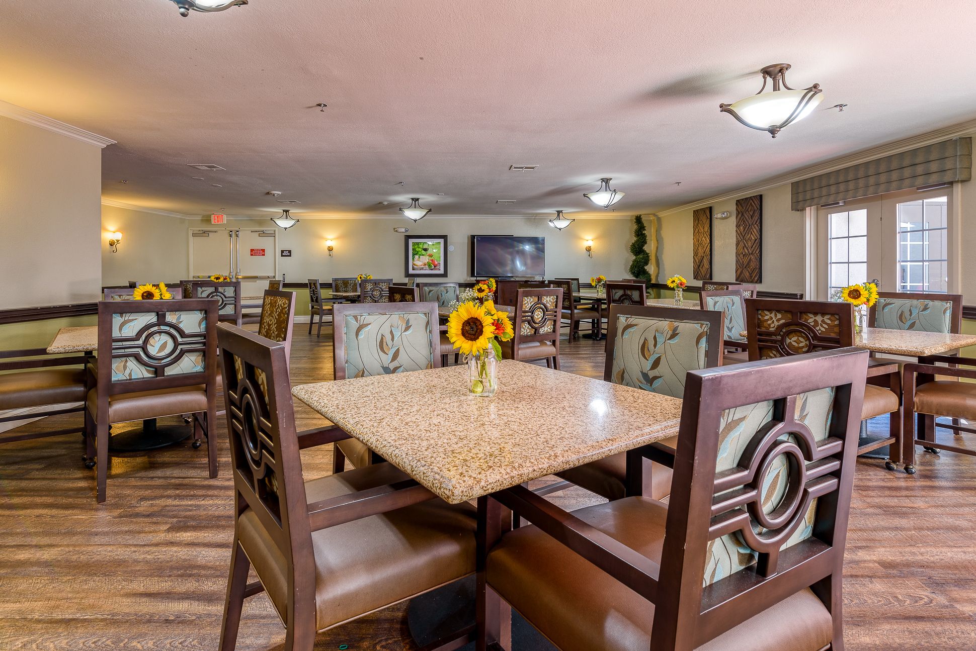 Interior view of Pacifica Senior Living South Coast with hardwood floors, dining area, and art decor.