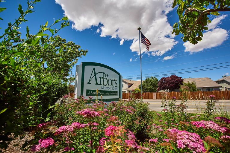 Arbors Memory Care senior living community with lush gardens and modern architecture in a suburban setting.