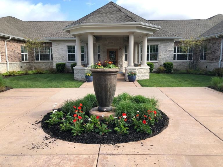 Exterior view of Eagles Nest Assisted Living community featuring a portico, lush grass, and plants.