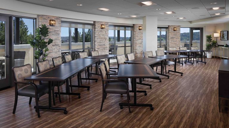 Interior view of Belmont Village Senior Living Aliso Viejo's cafeteria with wooden furniture and flooring.