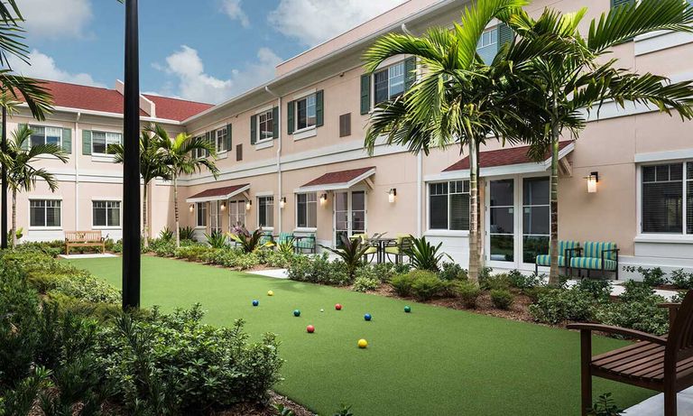 Senior living community, HarborChase of Wellington Crossing, featuring lush lawns, modern architecture, and comfortable outdoor furniture.