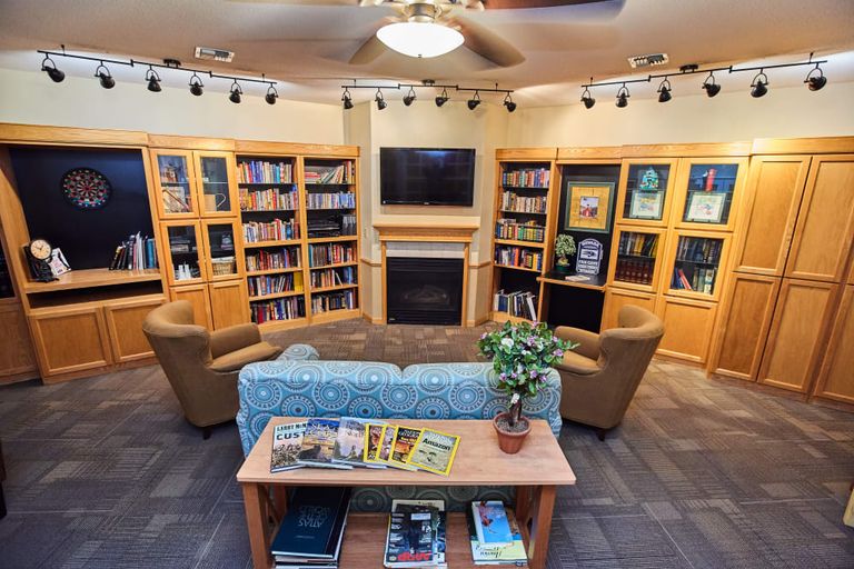 Interior view of Arbors Memory Care library with bookcases, fireplace, and computer station.
