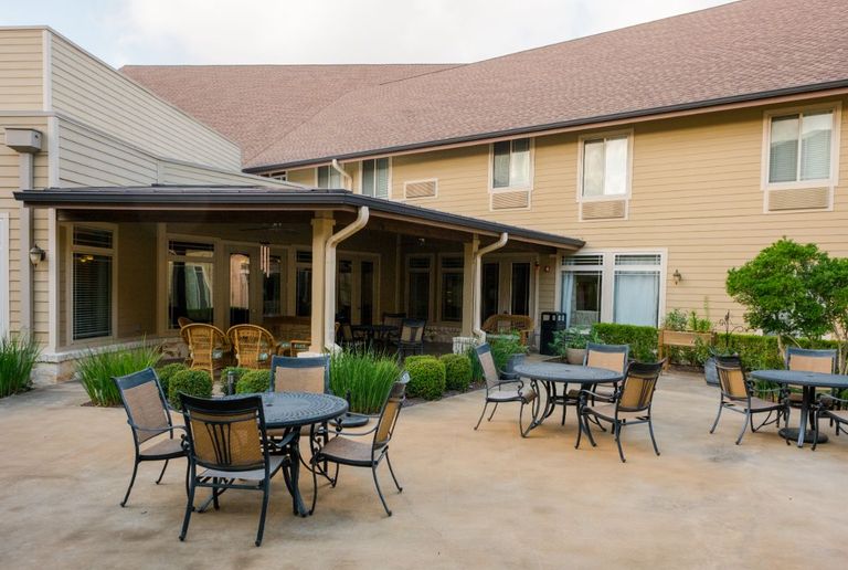 Senior living community, The Pavilion At Great Hills, featuring patio with dining table and lush backyard.
