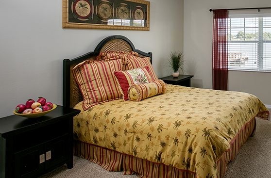 Interior design of a bedroom in Water's Edge senior living community, Lake Wales, featuring home decor and fresh apples.